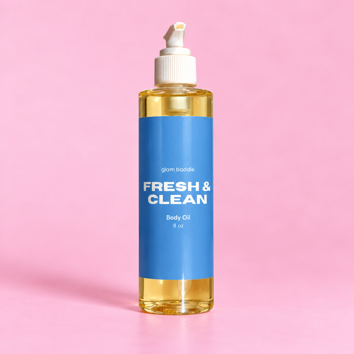 Glam Baddie Fresh & Clean Body oil 8 oz bottle with blue label on a pink background.