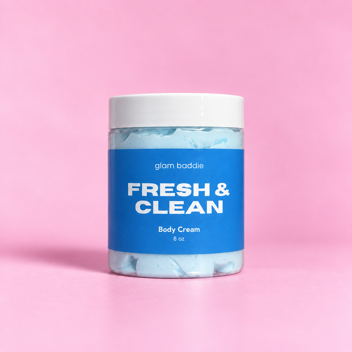 Glam Baddie Fresh and Clean Body Cream 8 oz jar with blue label on a pink background.